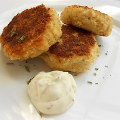 three crab cakes on a plate with sour cream