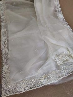 This is a fascinating pure organza silk saree in gorgeous white color, monochrome look. Saree features a dazzling beads and pearl work embroidery of floral design throughout the edges of the saree. Simple pearl work is twinkling all over the body of the saree. The beads and pearl embroidery are delicately hand embellished. Organza is a lightweight plain weave fabric. The pure organza attributes to a very comfy and flowy drape. Organza is considered as one of the most stylish and glamorous wear. Wedding Dupatta With Pearl Embroidery In Raw Silk, Wedding Raw Silk Dupatta With Pearl Embroidery, White Pearl Embroidered Dupatta, White Georgette Dupatta With Pearl Embroidery, Festive White Dupatta With Pearl Embroidery, Wedding Silk Saree With Pearl Embroidery, Festive White Pearl Embroidery Dupatta, Silk Dupatta With Pearl Embroidery For Wedding, Elegant Saree With Intricate Embroidery For Celebration