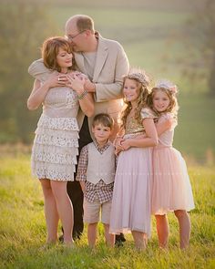 a family posing for a photo in a field with the sun shining down on them