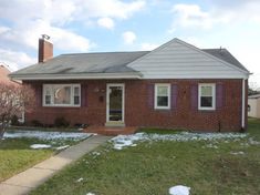 a red brick house with snow on the ground and grass in front of it,