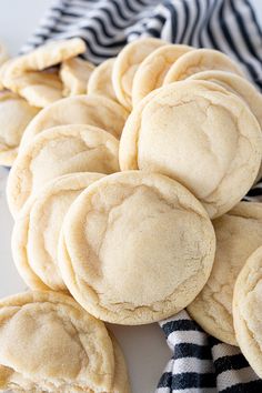 a pile of cookies sitting on top of a white plate next to a black and white striped towel