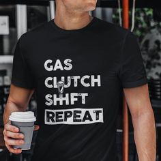 a man holding a coffee cup and wearing a black shirt with the words gas clutch shift repeat on it