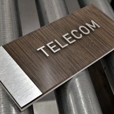 a sign that says telecom on it in front of some metal pipes and wires