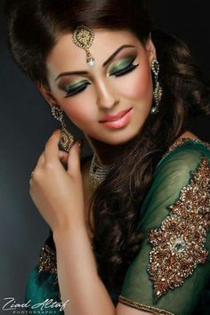 a woman with green eyeshade and gold jewelry on her head, posing for the camera