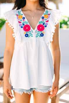 White Floral Embroidered Pompom Flutter Blouse Summer V-neck Blouse With Floral Embroidery, Summer V-neck Top With Geometric Embroidery, Summer V-neck Tops With Tassels, Summer V-neck Top With Tassels, Multicolor Embroidered V-neck Top For Vacation, Sleeveless Embroidered Tops For Brunch, Vacation V-neck Blouse With Embroidered Hem, V-neck Blouse With Embroidered Hem For Vacation, Chic Embroidered Tops For Vacation