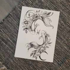 a piece of paper with an image of a fish and flowers on it sitting on a table