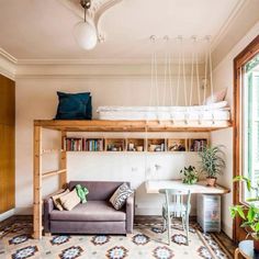 a living room with a couch, desk and bookshelf above the bunk bed