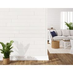 a living room with white walls and wooden floors, two plants on the side of the wall