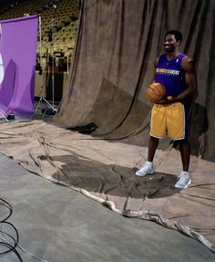 two basketball players standing in front of a purple and white backdrop with one holding a ball