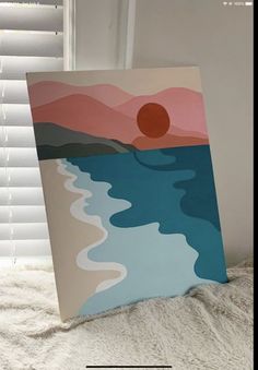 a painting is sitting on a bed next to a window with the sun setting behind it