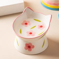 two bowls with flowers painted on them sitting on a table next to plates and cups