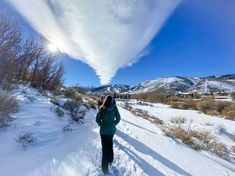 a woman is walking through the snow with her back to the camera and looking up into the sky