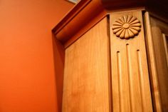 an orange wall with a wooden door and handle on the top part of it, next to a window