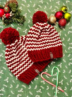 a red and white knitted hat next to candy cane on a green tablecloth