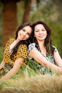 two women are posing for a photo in tall grass and trees, one is holding her arm around the other's shoulder