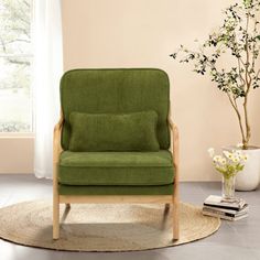 a green chair sitting on top of a rug next to a vase filled with flowers