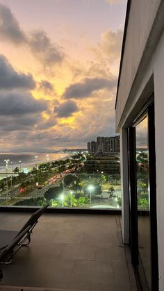 a balcony with a view of the ocean and city lights at sunset or dawn from an apartment building