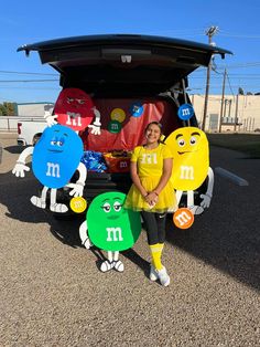 a woman standing in front of an open trunk with m and m characters on it