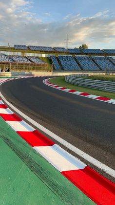 an empty race track with the sun shining on it's side and lots of seats in the background