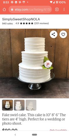 a white wedding cake sitting on top of a table next to a wooden wall with flowers