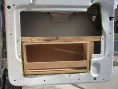 the inside of a white truck with a wooden shelf in it's back door