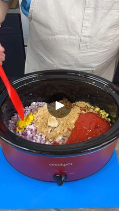 a person stirring ingredients in a crock pot with a red spatula to stir them