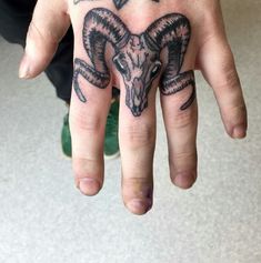 a hand with a goat head tattoo on it