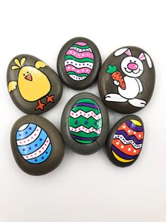 six painted rocks with cartoon easter eggs on them