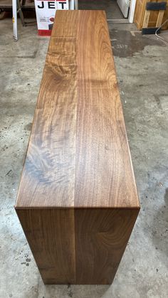 a very large wooden table sitting in a room next to some shelves and cabinets on the floor