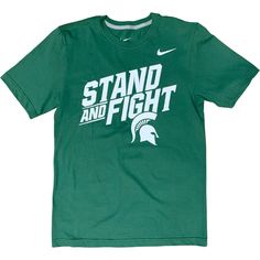 Kelly green crewneck short-sleeve t-shirt. A white Nike swoosh is on the upper left chest. On the center chest is large all caps text reading Stand and Fight above a Spartan helmet Helmet Logo, Actions Speak Louder, Actions Speak Louder Than Words, Nike Tees, Michigan State, Shirt Designs, Nike, Mens Graphic Tshirt, Mens Tshirts