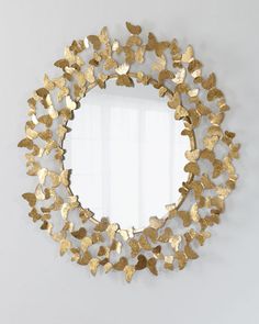 a round mirror with gold butterflies on the front and sides, hanging on a wall