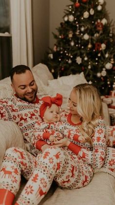 a man and woman in christmas pajamas holding a baby