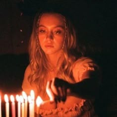 a woman holding a lit candle in front of a cake with many candles on it