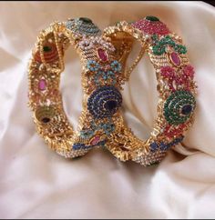 two gold bracelets sitting on top of a white cloth