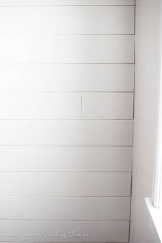 a white painted wall in a room with wood flooring and wooden slatted walls