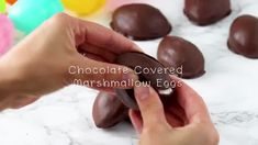 chocolate covered marshmallow eggs being held by someone's hand with the words chocolate covered marshmallow eggs in front of them