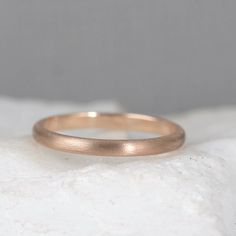 a gold wedding band sitting on top of a white rock in front of a gray background