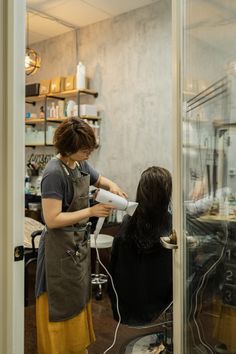 a woman is getting her hair done in a salon while another person works on it