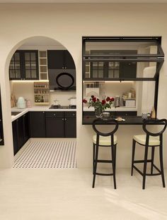 the kitchen is decorated in black and white with two stools at the bar area