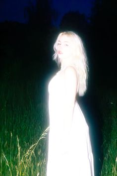 a woman standing in tall grass at night