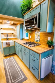 a kitchen with blue cabinets and green walls, wood flooring and wooden counter tops