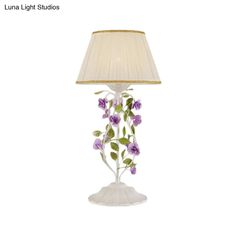 a lamp that has flowers on it and a shade over the lamp is white with purple flowers