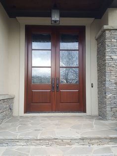 the front door to a house with two double doors and stone steps leading up to it