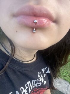 a close up of a person with a piercing on their nose and grass in the background