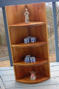 a wooden shelf sitting on top of a porch next to a doll and some jars