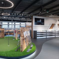 an indoor golf course with artificial turf and wooden boards on the wall, in front of large windows