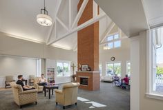 two people sitting in chairs inside of a large room with high ceilings and exposed beams