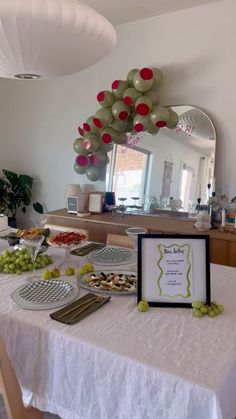 a white table topped with plates and trays filled with food next to a mirror