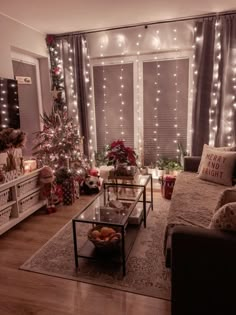 a living room decorated for christmas with lights and decorations on the windowsills, couches, coffee table and television