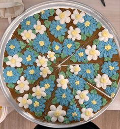 a cake decorated with blue, yellow and white flowers on top of a metal pan